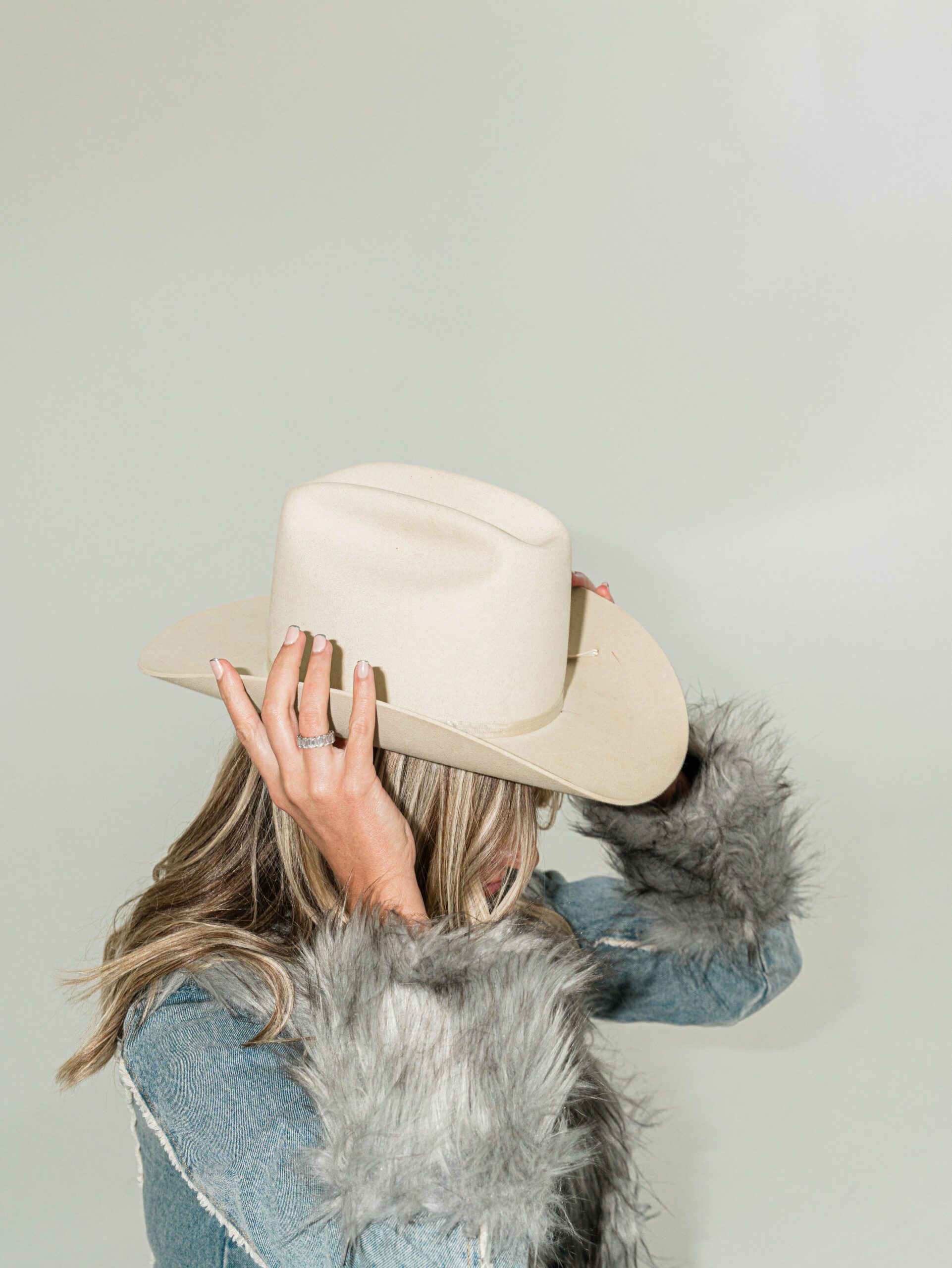 Woman holding her hat and showing manicured nails in Columbus